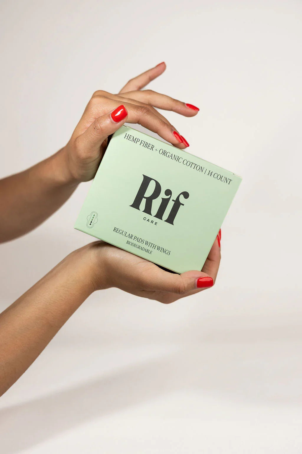 Hands holding a box of hemp fiber organic cotton biodegradable period pads against a plain background.