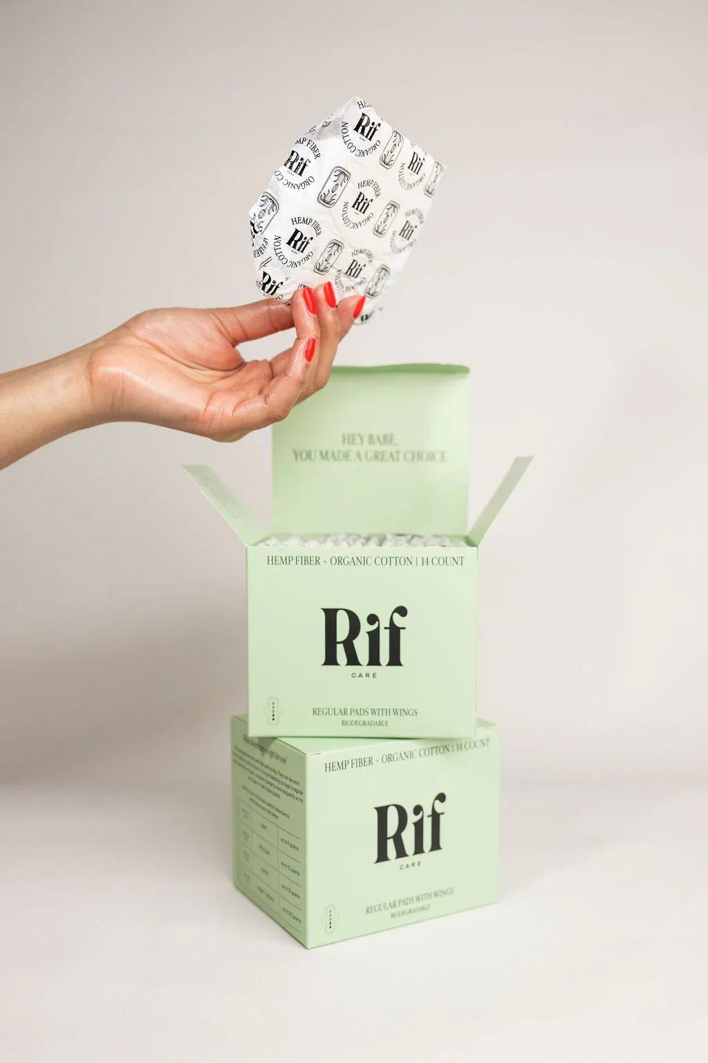 Hand holding organic cotton hemp fiber pad above green biodegradable Rif pads box