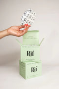 Hand holding organic cotton hemp fiber pad above green biodegradable Rif pads box