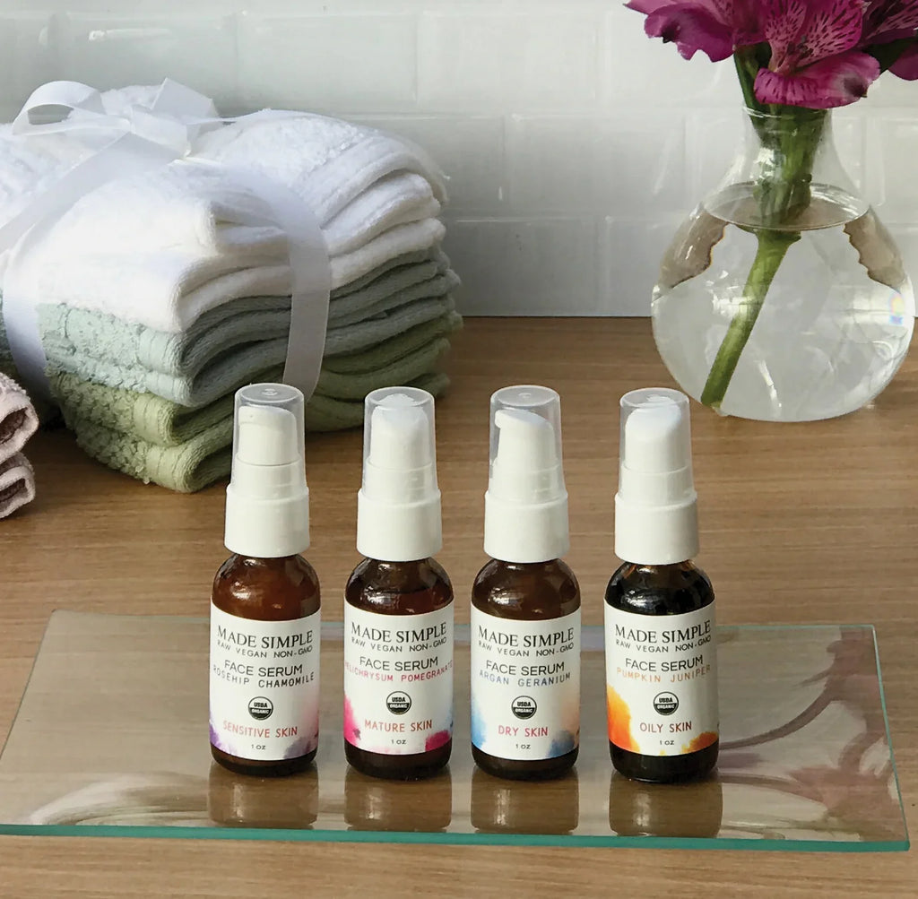Four organic face serums for sensitive, mature, dry, and oily skin on a bathroom counter