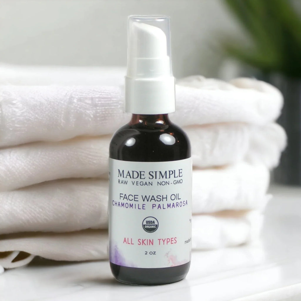 Organic face wash oil bottle with pump, labeled chamomile palmarosa, on white towels