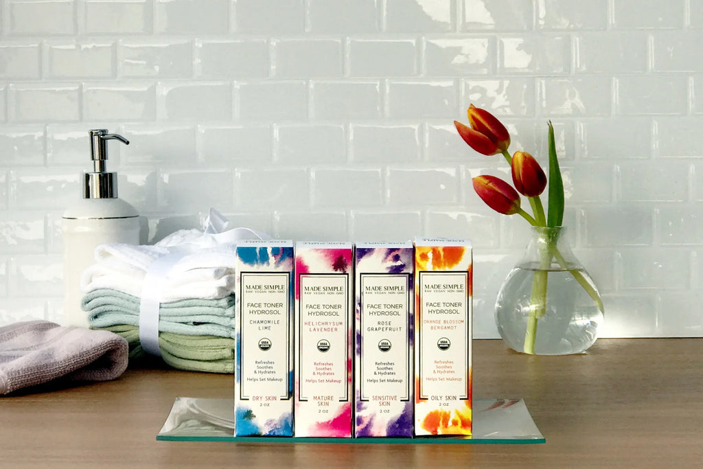 Organic face toner hydrosol products with towels, soap dispenser, and tulips on counter