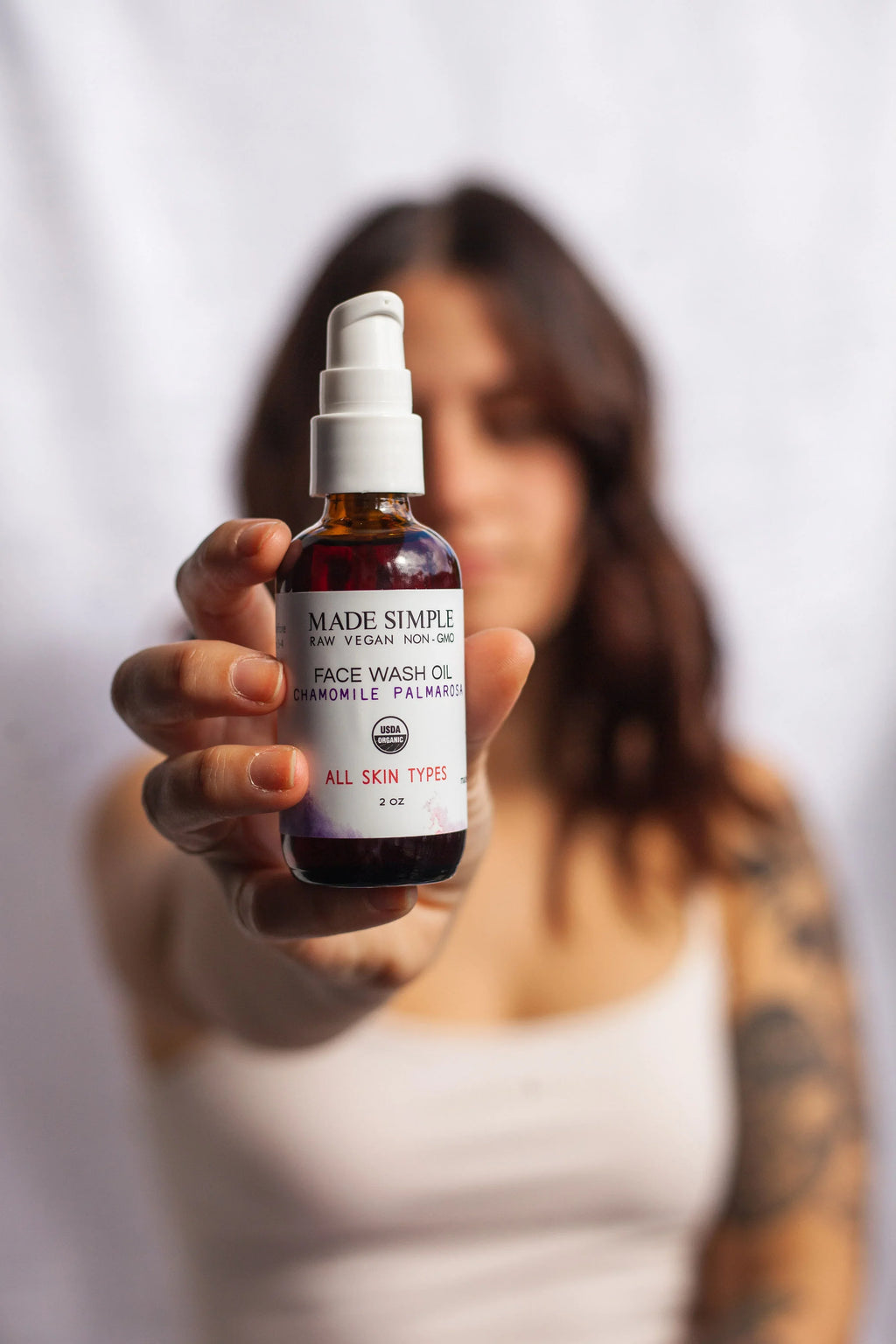 Woman holding bottle of organic vegan face wash oil for all skin types, natural skincare